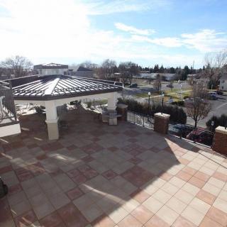 A sunny view of a suburban terrace with tiled flooring and distant greenery.