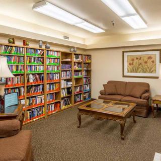 A cozy library with bookshelves, sofas, and a coffee table.