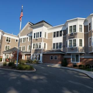 A residential apartment building with an American flag in the foreground.