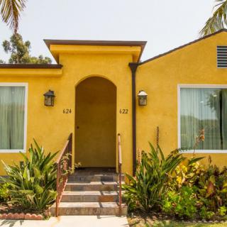 A cozy yellow house with a welcoming front entrance and lush greenery.