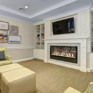 A cozy living room with a modern fireplace, a wall-mounted TV, and comfortable seating.