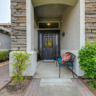 A welcoming front porch with a wreath on the door and a bench, surrounded by stone walls and greenery.