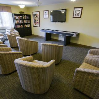 A cozy lounge area with striped chairs facing a television and bookshelf.