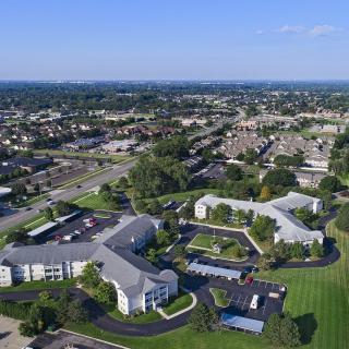Aerial view of a suburban residential area with green spaces and multiple buildings.