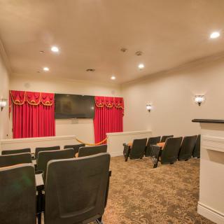 A cozy home theater with comfortable seating, red curtains, and a large screen.