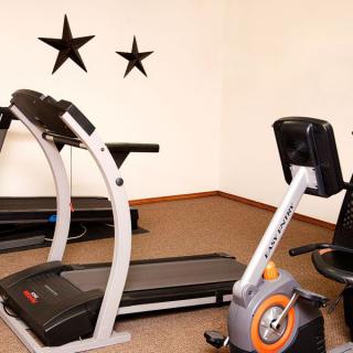 A small workout room with a treadmill and an exercise bike, decorated with star accents on the wall.