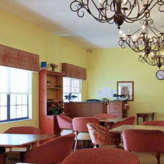 An empty cafe interior with tables and chairs, adorned with chandeliers.
