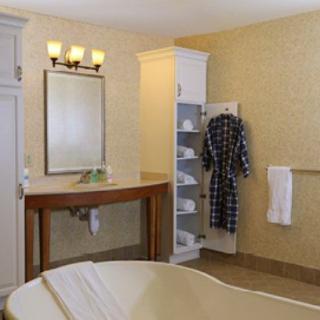 A stylish bathroom with a mirror, sink, robe on a wall hook, and neatly arranged shelves.