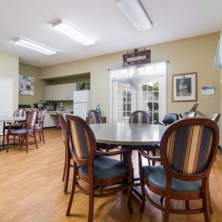A cozy dining area with tables and chairs, adjacent to a small kitchen.