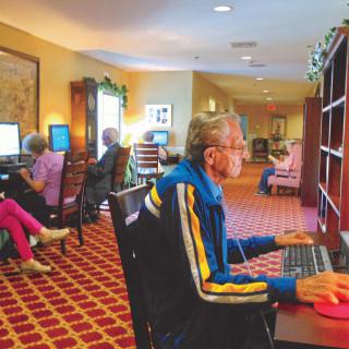Seniors engaged with computers in a library setting.