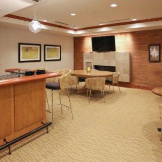 A modern living room with bar and seating area, featuring wood paneling and a fireplace.