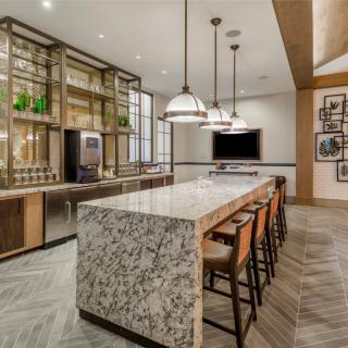 A modern kitchen with a large island countertop and stylish bar stools, illuminated by elegant pendant lights.