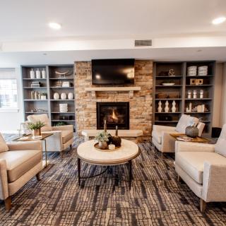 A modern and cozy living room featuring a stone fireplace, comfortable seating, and built-in bookshelves.