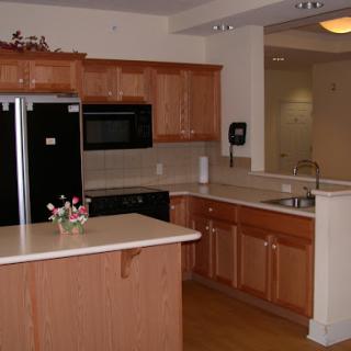 A modern kitchen featuring wooden cabinets and black appliances.
