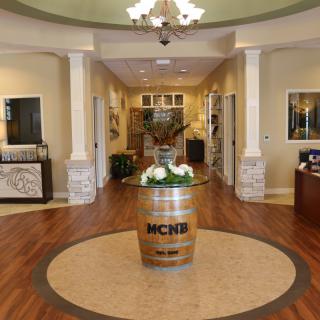 A welcoming lobby interior with elegant decor, featuring a chandelier and a decorative barrel centerpiece.