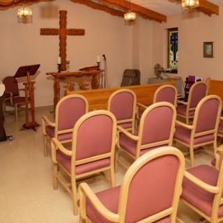A serene interior view of a church with seating and a wooden cross.
