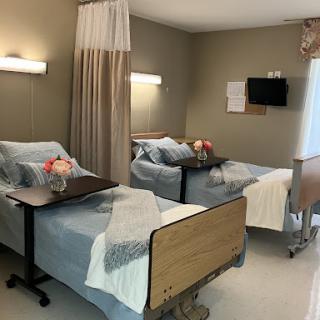 A well-equipped patient room featuring two hospital beds, complete with bedding and personal touches.