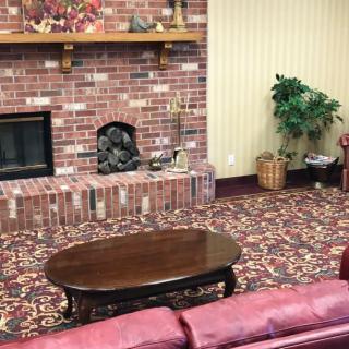 A cozy living room featuring a brick fireplace, patterned carpet, and comfortable seating.