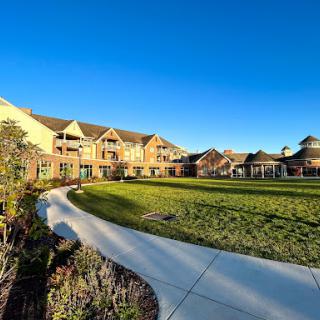 A picturesque view of a modern building set against a clear blue sky, featuring well-maintained green spaces and a winding pathway.