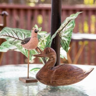 Wooden bird sculptures on an outdoor table with leaf decorations.