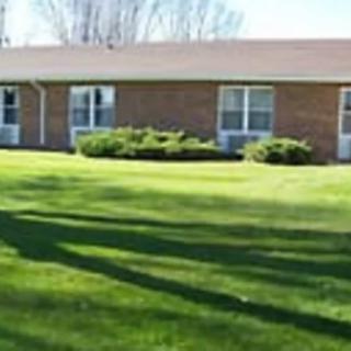 A single-story brick building with a neatly maintained lawn and bushes.
