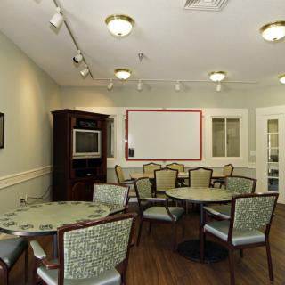 A well-lit meeting room with multiple tables, chairs, and a whiteboard.