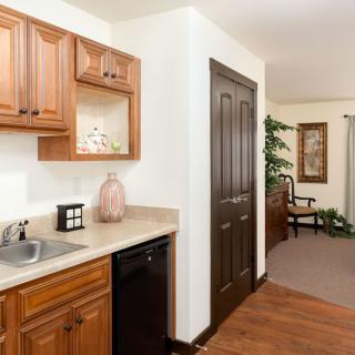 A cozy kitchen space featuring wooden cabinets and a small sink with adjacent living area.