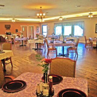 A cozy dining area with neatly arranged tables and chairs, featuring floral centerpieces.