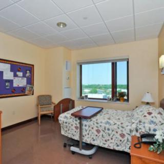 A clean and well-organized hospital room with a single bed and large window.