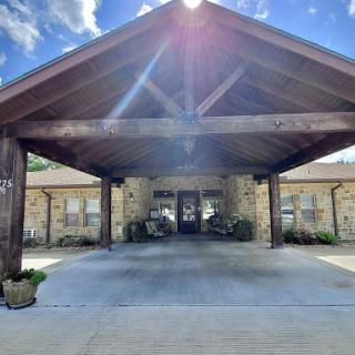 A picturesque entrance featuring a wooden canopy and stone facade, illuminated by the sun.