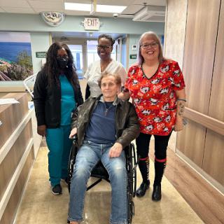 A group of caregivers and a patient share a moment in a healthcare facility.