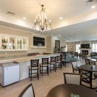 A spacious modern kitchen and dining area featuring a bar with high chairs, a chandelier, and comfortable seating.