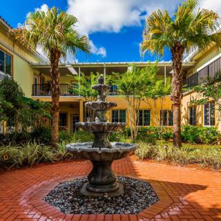 A beautiful courtyard with a central fountain surrounded by lush palm trees and vibrant architecture.