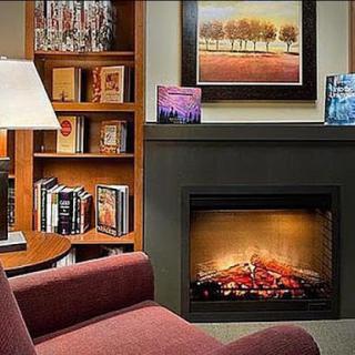 A cozy living room featuring a warm fireplace, a bookshelf filled with books, and comfortable seating.