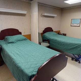 A hospital room with two beds separated by a curtain divider.