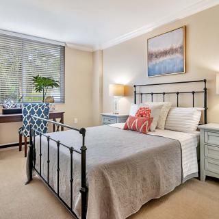 A cozy bedroom with a metal frame bed, patterned chair, and decorative elements.