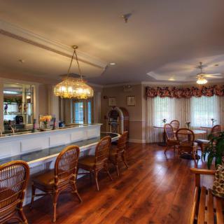 A traditional dining area with wooden flooring, a bar counter, and decorative chandeliers.