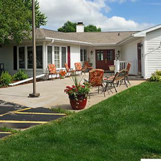 A cozy house with a furnished patio and lush green lawn.