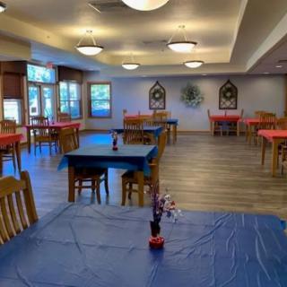An empty dining room with tables covered in colorful tablecloths and simple decorations.