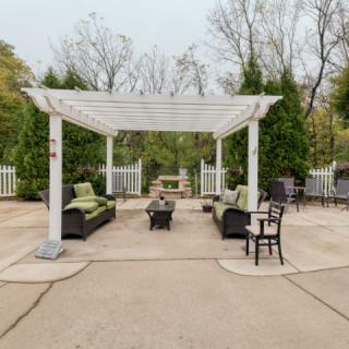 A backyard patio with a white pergola and outdoor seating area.