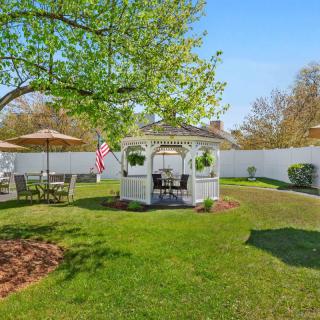 A peaceful garden with a gazebo surrounded by lush greenery and outdoor seating.