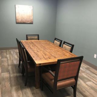 A simple meeting room with a wooden conference table and six chairs.