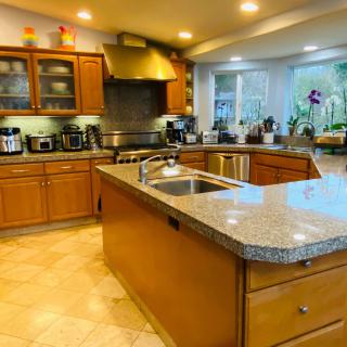 A modern kitchen with an island, featuring wood cabinets and various appliances.