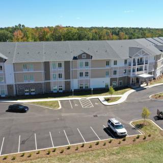 Aerial view of a suburban apartment complex with a parking lot and surrounding greenery.