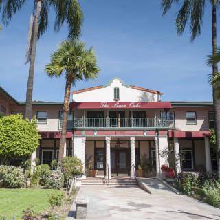 A hotel entrance surrounded by palm trees and a clear blue sky.