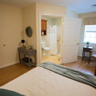 A cozy bedroom with an attached bathroom, featuring simple decor and comfortable furnishings.