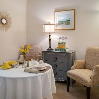 Cozy living room corner with a round table, two chairs, a lamp, and decorative elements.