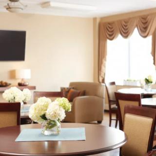 A cozy dining area with round tables, chairs, and floral centerpieces.
