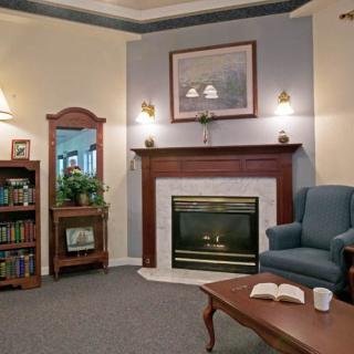 A cozy living room featuring a fireplace, armchair, and bookshelf.