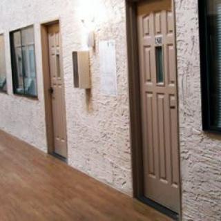 A corridor with multiple doors and a textured wall.